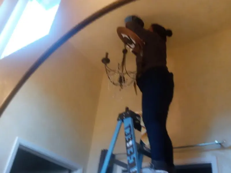 Electrician installing a chandelier in a Romulus residence